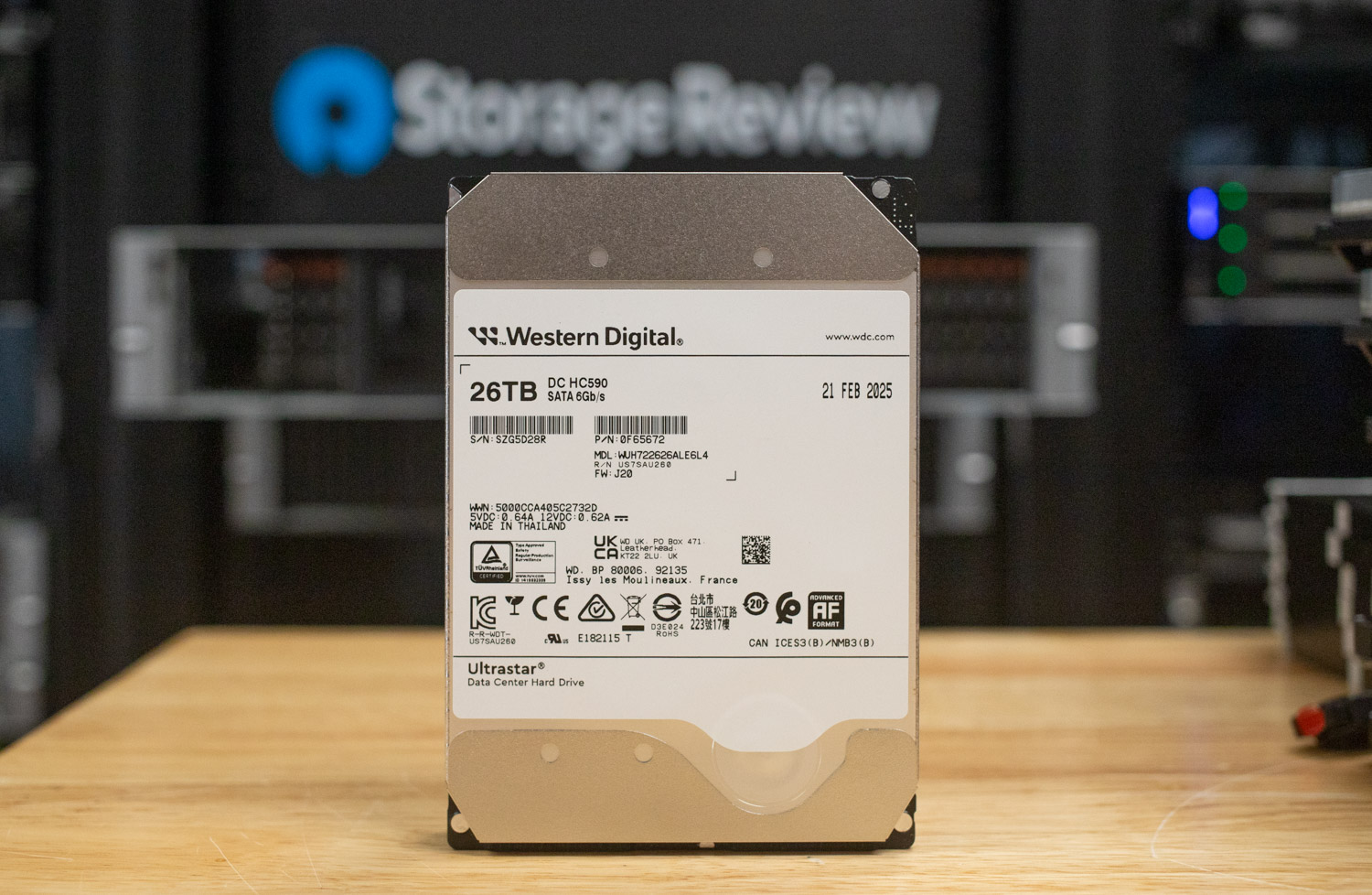 Western Digital Ultrastar DC HC590 26TB enterprise hard drive standing upright on a wooden surface.