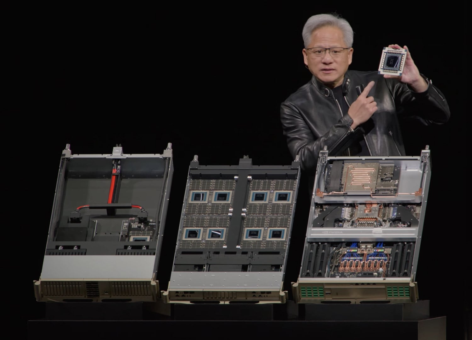 NVIDIA CEO Jensen Huang holding a Rubin GPU package beside three open Vera Rubin compute trays at GTC 2026