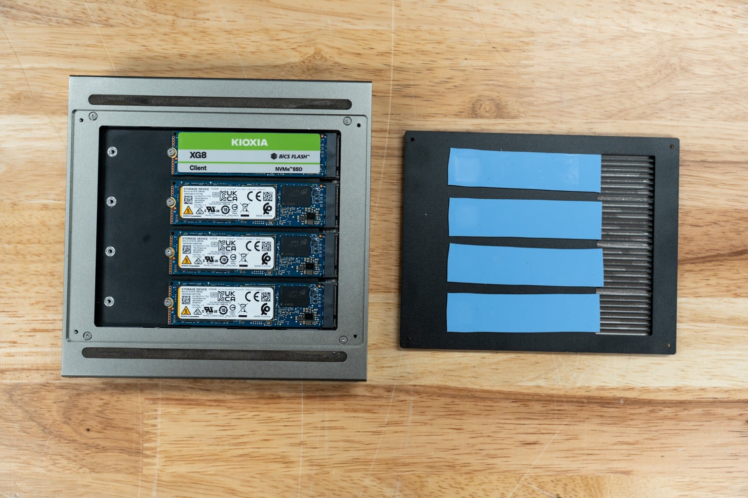 GP Spark opened beside its lid, with blue thermal pads coupling the four KIOXIA XG8 drives to the finned heatsink cover