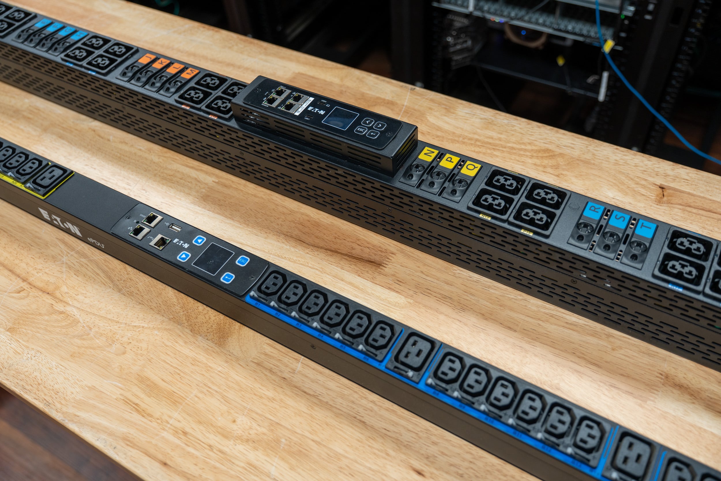 Two Eaton HDXL Rack PDUs on the bench showing the Gigabit Network Module LCD, Ethernet ports, and C39 outlets