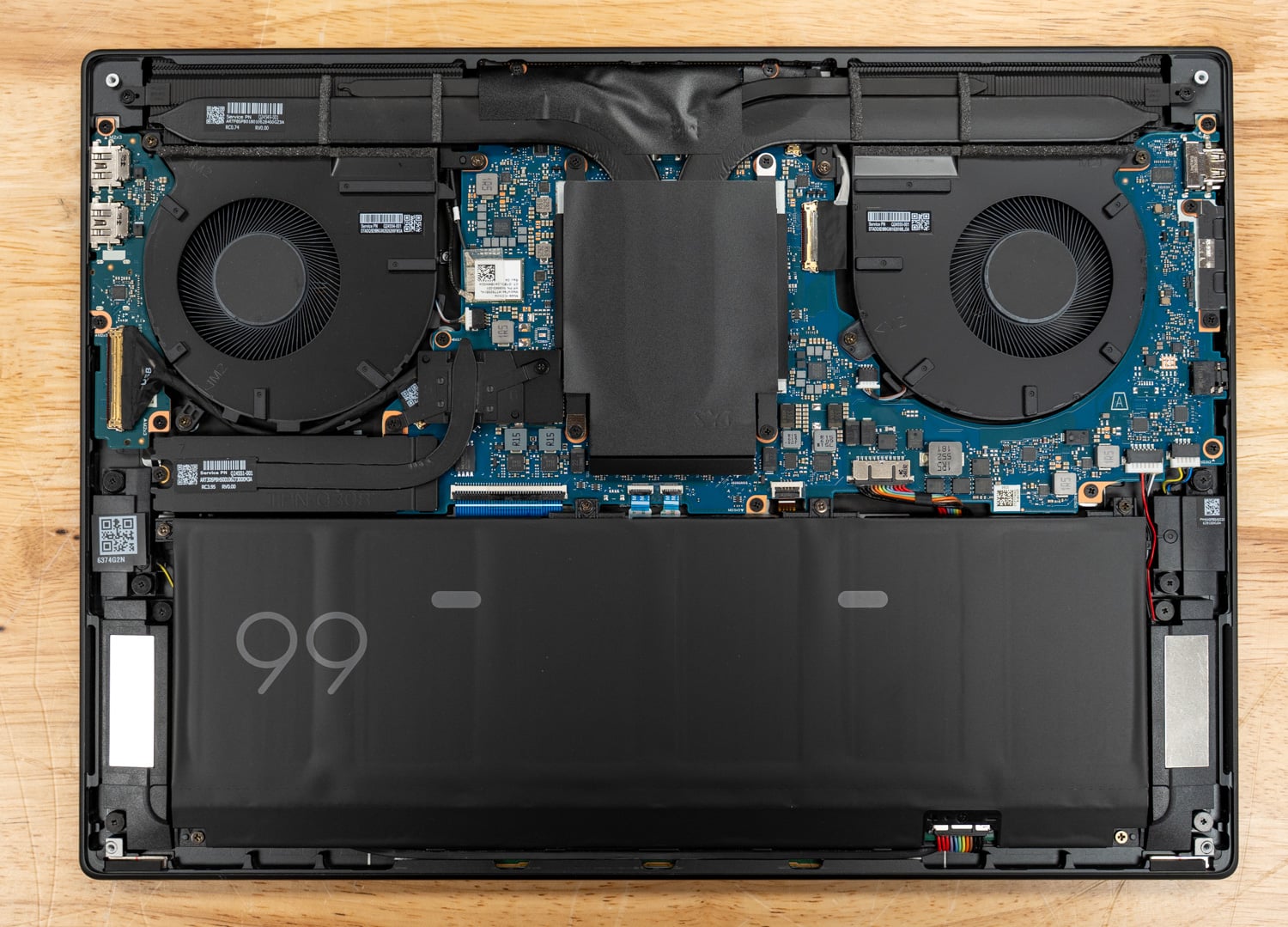 HP OmniBook Ultra 16 internals with the bottom panel removed: two fans, heat pipes, a shielded center section, and the 99Wh battery