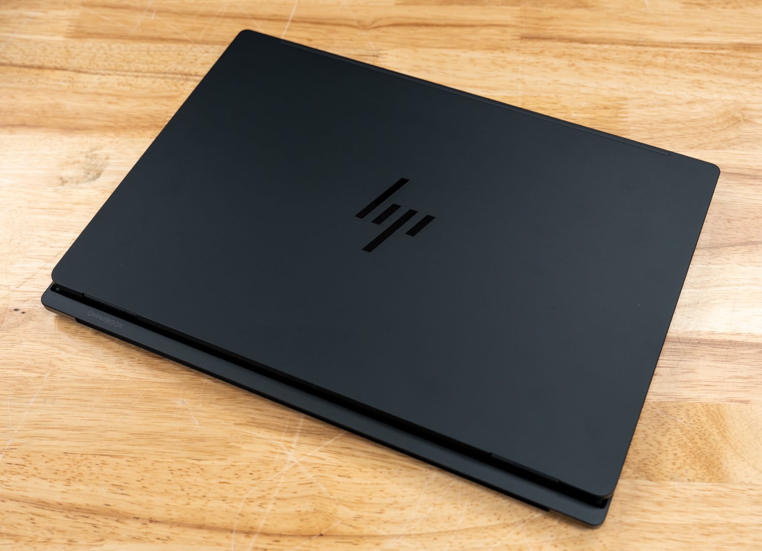 HP OmniBook Ultra 16 lid in Eclipse gray with the HP logo, closed on a wood surface