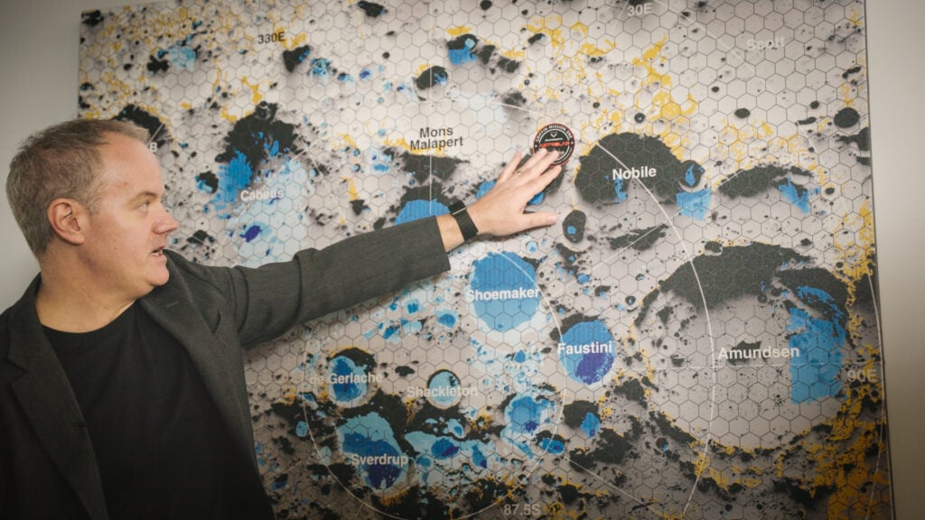 Astrolab CEO Jaret Matthews pointing to a map of the lunar south pole showing where FLIP will deploy, with permanently shadowed crater basins shaded in blue