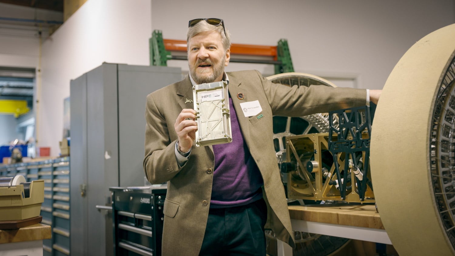 Dr. Mark Fernandez of HPE holding a mockup of HPE Spaceborne Computer-4, a flat aluminum compute module about 249 by 132 by 26 mm, at Astrolab in Los Angeles