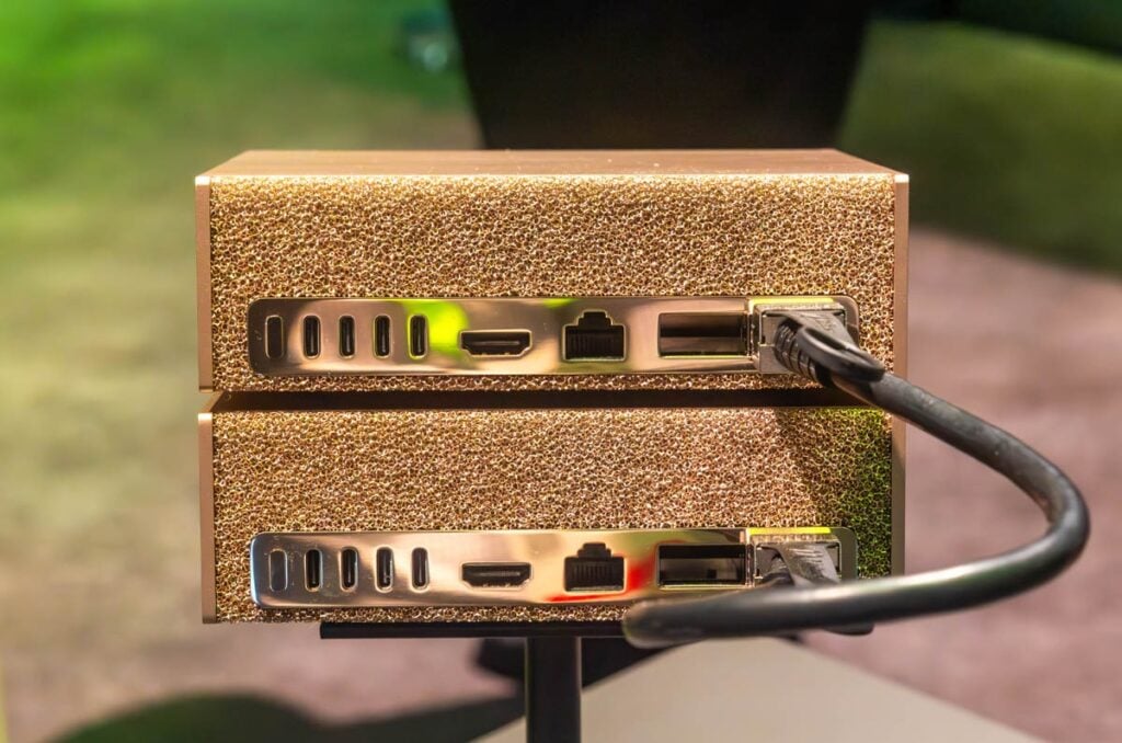 Two stacked NVIDIA DGX Spark units seen from the rear, with a QSFP cable looping between the ConnectX-7 ports to form a two-node cluster, the same link the 64GB DGX Spark uses to pair